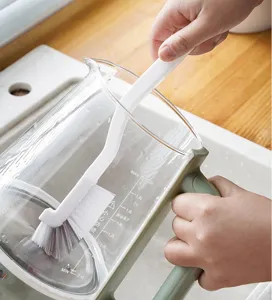 Nahaufnahme einer weißen Reinigungsbürste, die das Innere eines Glaskrugs reinigt.