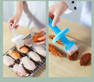 Macro view of blue and white silicone brushes applying seasoning to grilled chicken wings