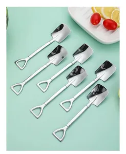 Set of six creative stainless steel shovel-shaped dessert spoons on green background