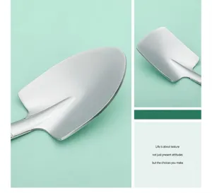 Macro detail of polished stainless steel shovel-shaped dessert spoons on green background