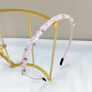 Close-up of a high-end handmade pink crystal rhinestone headband on an elegant gold stand