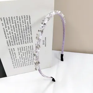 Close-up of a handmade lavender crystal headband with sparkling rhinestones on a white surface.