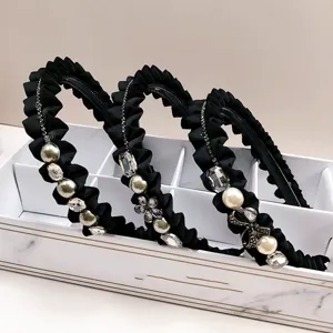 Luxury black pleated headbands decorated with crystals and pearls in a marble display box