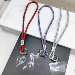 Détail montrant trois lanières de téléphone en strass en rouge, violet et argenté