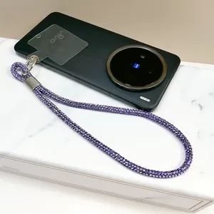 Gros plan d'une dragonne de téléphone en strass violets avec languette transparente