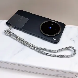 Détail d'un cordon de téléphone en strass étincelants sur un smartphone noir.