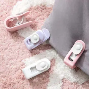 Set pastellfarbener Bettdecken-Clips auf flauschigem rosa Teppich und grauem Stoff