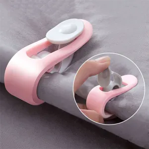 Bettdecken-Clips in Rosa und Grau zur Befestigung von Laken auf grauer Bettwäsche-Oberfläche
