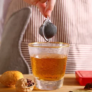 304 stainless steel mesh tea ball infuser being lifted from a glass of tea