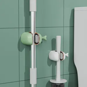 Detail view of whale-shaped wall-mounted mop and broom holder in a green tiled bathroom