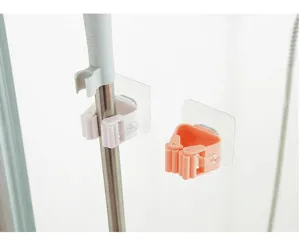 Close-up of wall-mounted adhesive mop holders in white and orange plastic materials