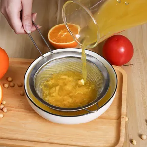 Colador de malla fina de acero inoxidable filtrando jugo de naranja fresco en un bol