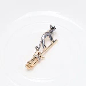 Detailed view of a creative flying cat on a broomstick brooch with crystal accents