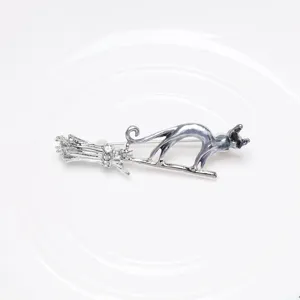 Close-up of a silver cat on a flying broomstick brooch with iridescent blue pearlescent finish