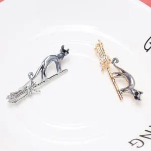 Detail view of creative flying broomstick cat brooches in polished gold and silver