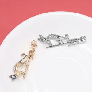 Detail view showing the back pin mechanism of gold and silver cat broom jewelry brooches.