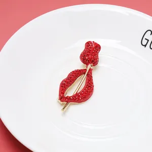Detailed view of elegant red rhinestone lips and rose brooch on a white ceramic plate