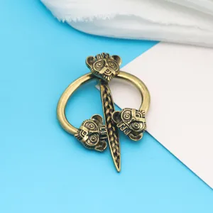 Spilla per mantello in stile vichingo vintage con tre maschere su un anello di bronzo.