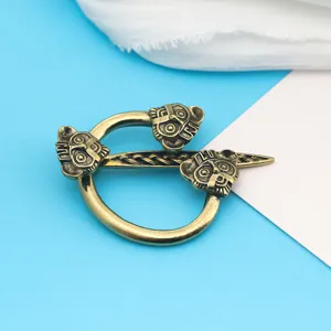 Dettaglio di una spilla vichinga in bronzo con maschere intagliate e trame intrecciate