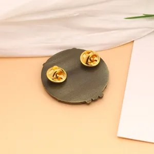 Detailed back view of retro Cthulhu pin with double golden butterfly clutches on a tan surface