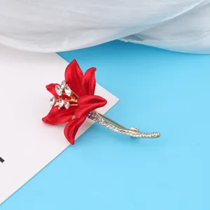 Elegant red lily flower brooch with clear rhinestones on a blue background