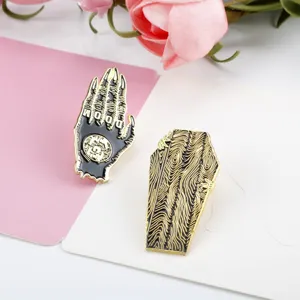 Detailed view of Halloween Gothic Doom hand and coffin wood grain enamel pins on pink background.