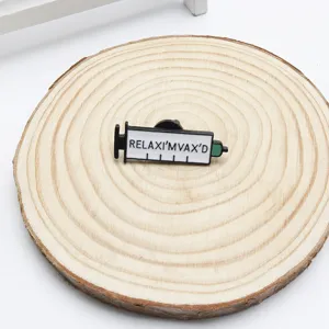Gros plan d'une broche créative en émail en forme de seringue avec 'RELAXI'MVAX'D'