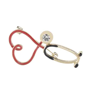 Close-up detail of a gold-tone stethoscope heart brooch featuring red and black enamel finish