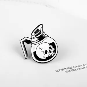 Detailansicht eines schwarz-weißen Emaille-Pins mit einem Totenkopf im Teekessel