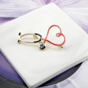 Close-up of a heart-shaped stethoscope brooch with red enamel and rhinestone detail