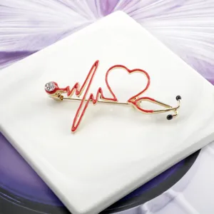 Close-up detail of a gold-toned red heart stethoscope brooch for doctors and nurses