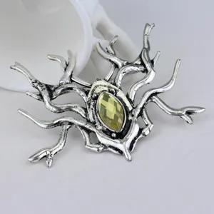 Macro detail of a vintage silver gothic branch brooch featuring a yellow faceted gem