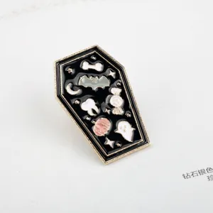 Close-up of a cartoon coffin enamel pin with Halloween motifs like bats and ghosts.