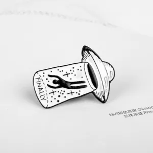 Detailed close-up of a black and white UFO abduction enamel pin featuring FINALLY text