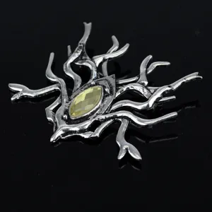 Detail view of a gothic spider-inspired brooch with yellow-green faceted gemstone