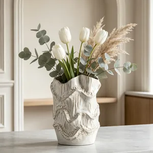 Elegant cream textured ceramic vase with wavy rim holding white tulips in a room