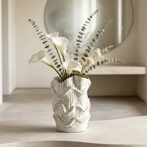 Artistic ceramic vase with wavy texture featuring elegant white calla lilies arrangement