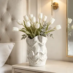 Close-up of artistic wavy textured ceramic vase with white tulips on bedside