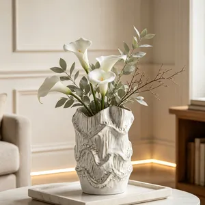 Detailed view of textured ceramic vase with elegant wave rim and white calla lilies