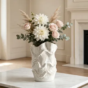 Artistic wavy ceramic vase with elegant flower arrangement on white marble table
