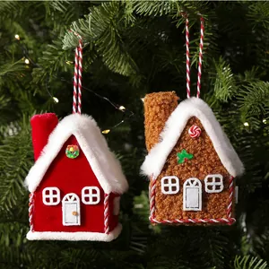 Close-up of red and brown plush house Christmas tree ornaments hanging on a lighted pine tree.