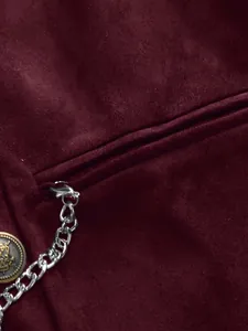 Close-up detail of a burgundy velvet vest featuring a metallic chain and crest button