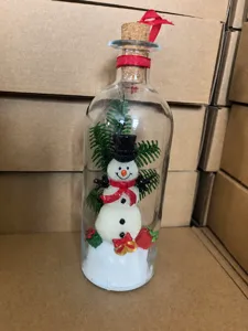 Detail view of a Christmas snowman figurine inside a glass message bottle with cork.