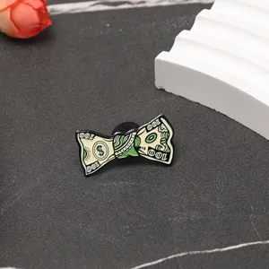 Gros plan d'une broche en métal créative en forme de billet de dollar plié.