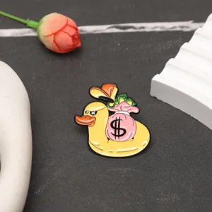 Détail d'une broche en émail canard de bain portant un sac d'argent rose avec un dollar