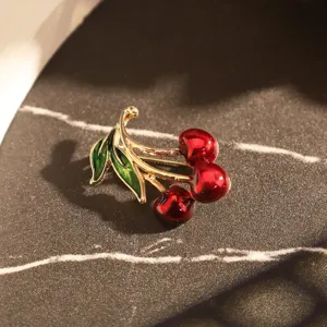 Gros plan d'une élégante broche cerise avec des fruits rouges brillants et des feuilles