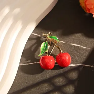 Vue détaillée d'une broche cerise créative avec émail rouge et finition dorée élégante