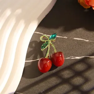 Vue détaillée d'une broche cerise avec cristaux verts étincelants et fruits rouges