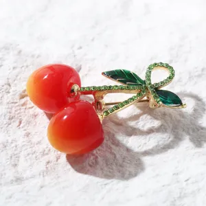 Gros plan sur l'élégante broche cerise avec tiges serties de cristaux et fruits rouges.