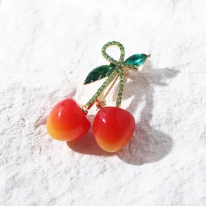 Vue détaillée d'une broche cerise en strass étincelants avec une finition rouge brillante.